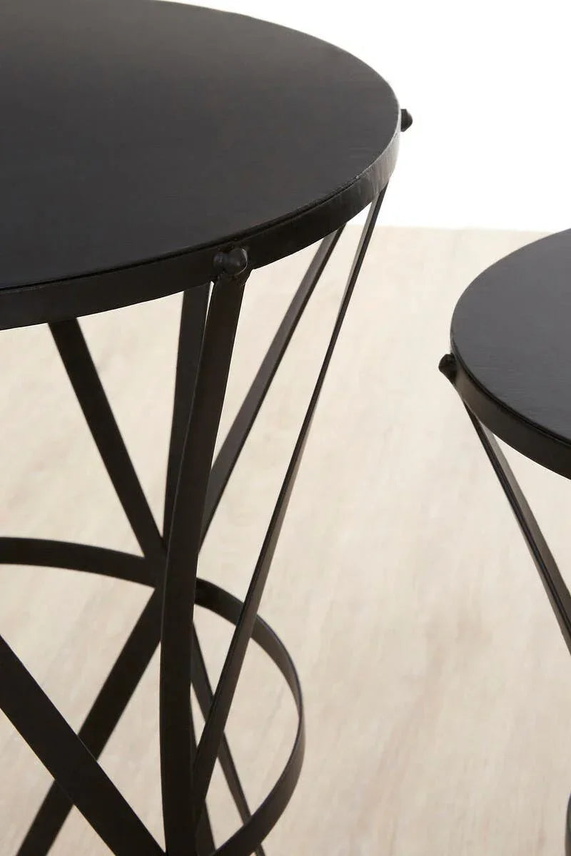 Black metal nesting tables with round tops and crisscross legs on light wood floor