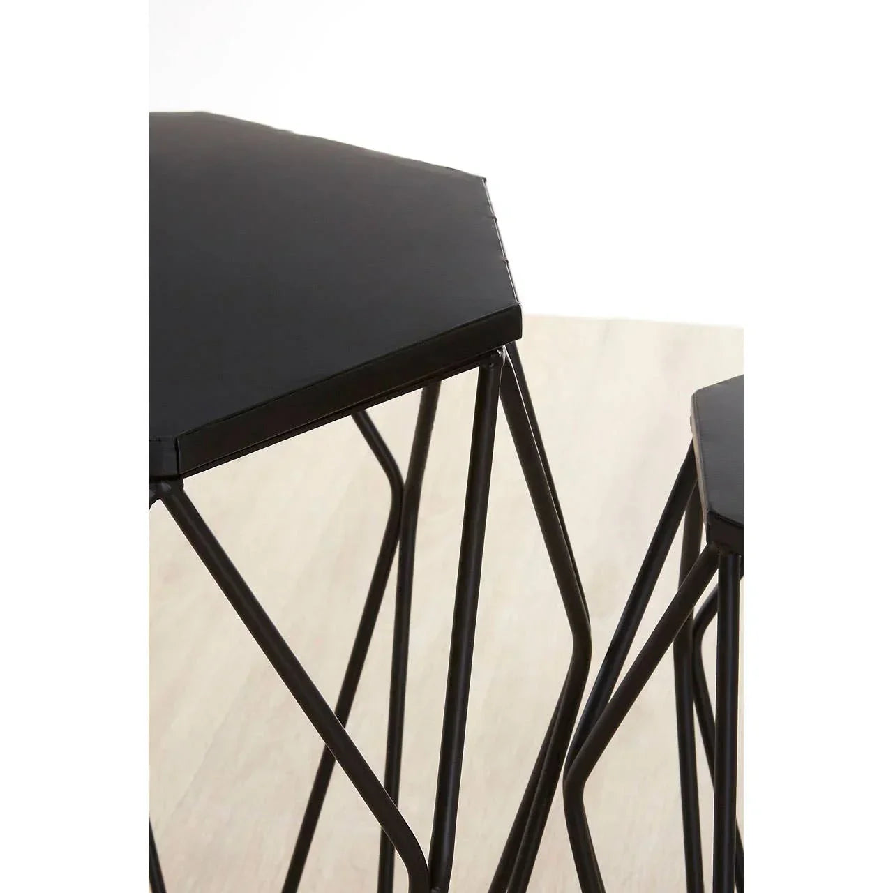 Black metal hexagon nesting tables with geometric legs on light wood floor
