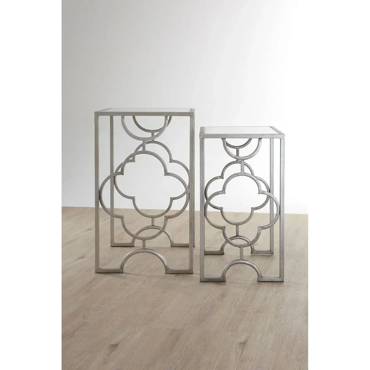 Set of two silver metal side tables with geometric frame design on wooden floor