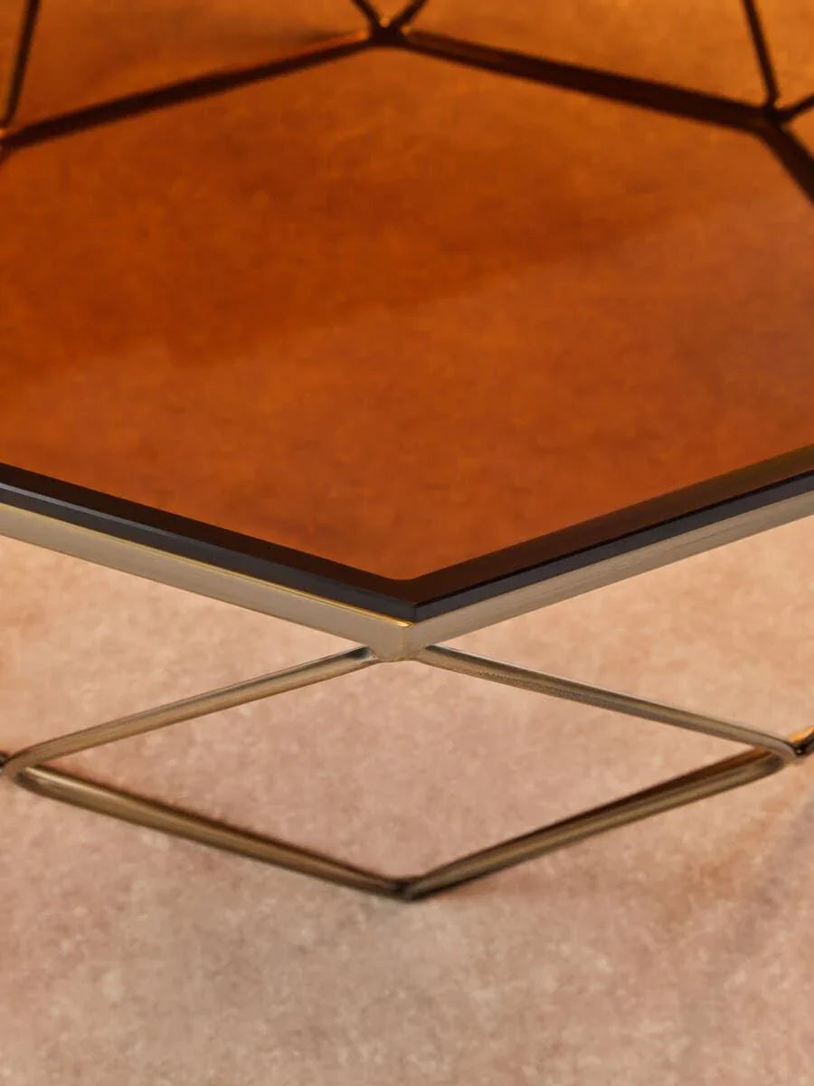 Hexagonal glass coffee table with gold metal frame on beige carpet