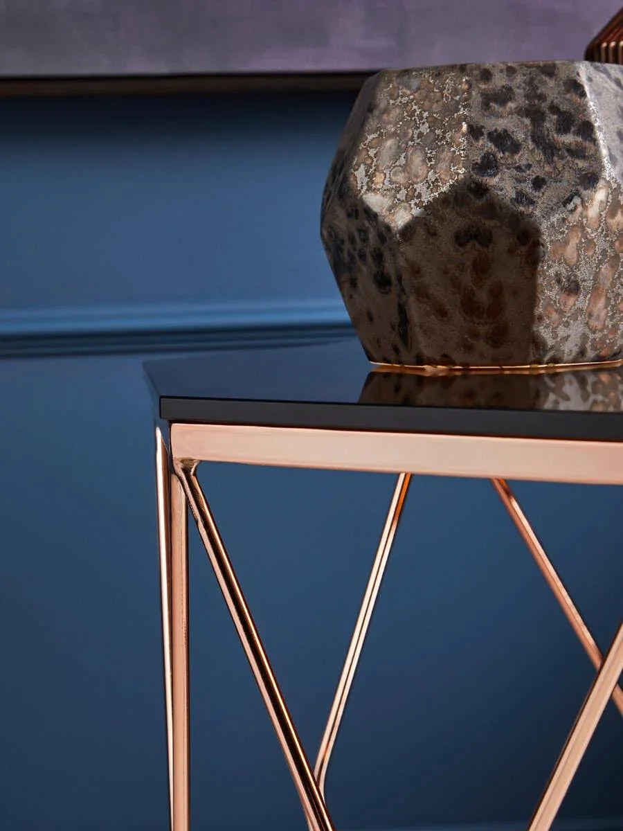Glass top side table with gold metal frame and decorative stone vase