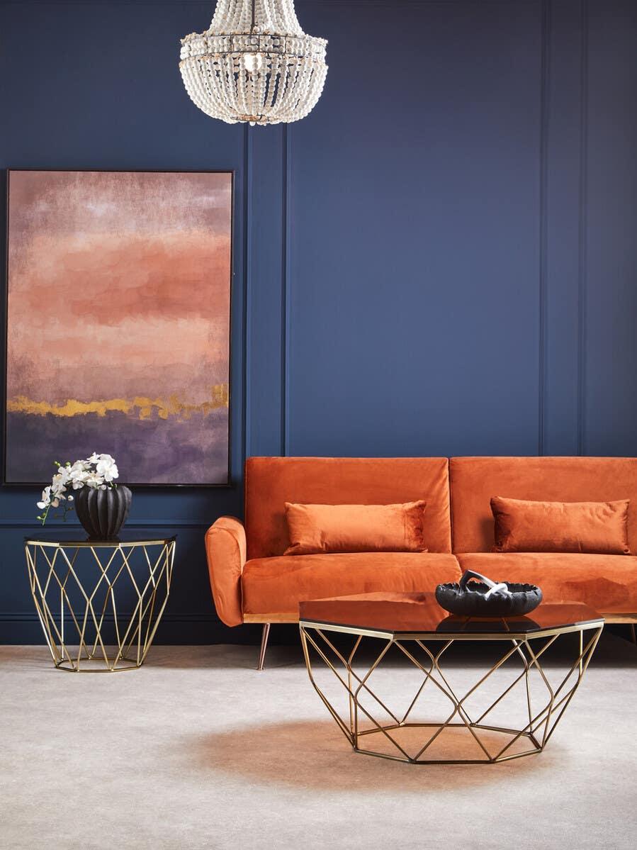 Orange velvet sofa with gold coffee table and side table in modern living room setting