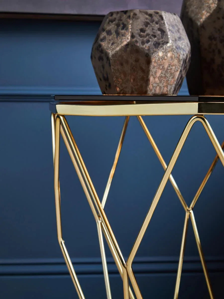 Gold metal side table with glass top and geometric base, decorative vase displayed