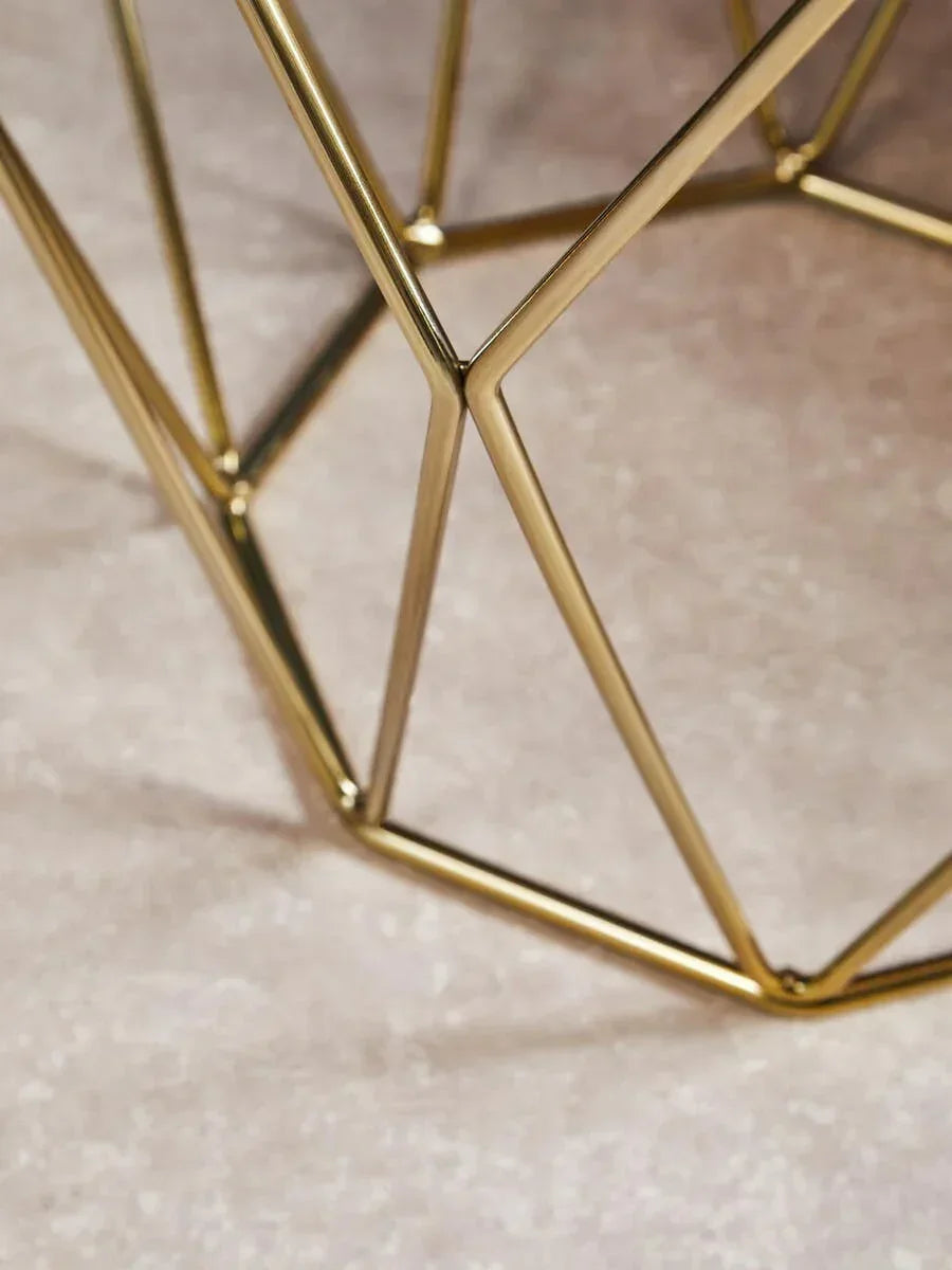 Gold metal table base with geometric design on stone flooring