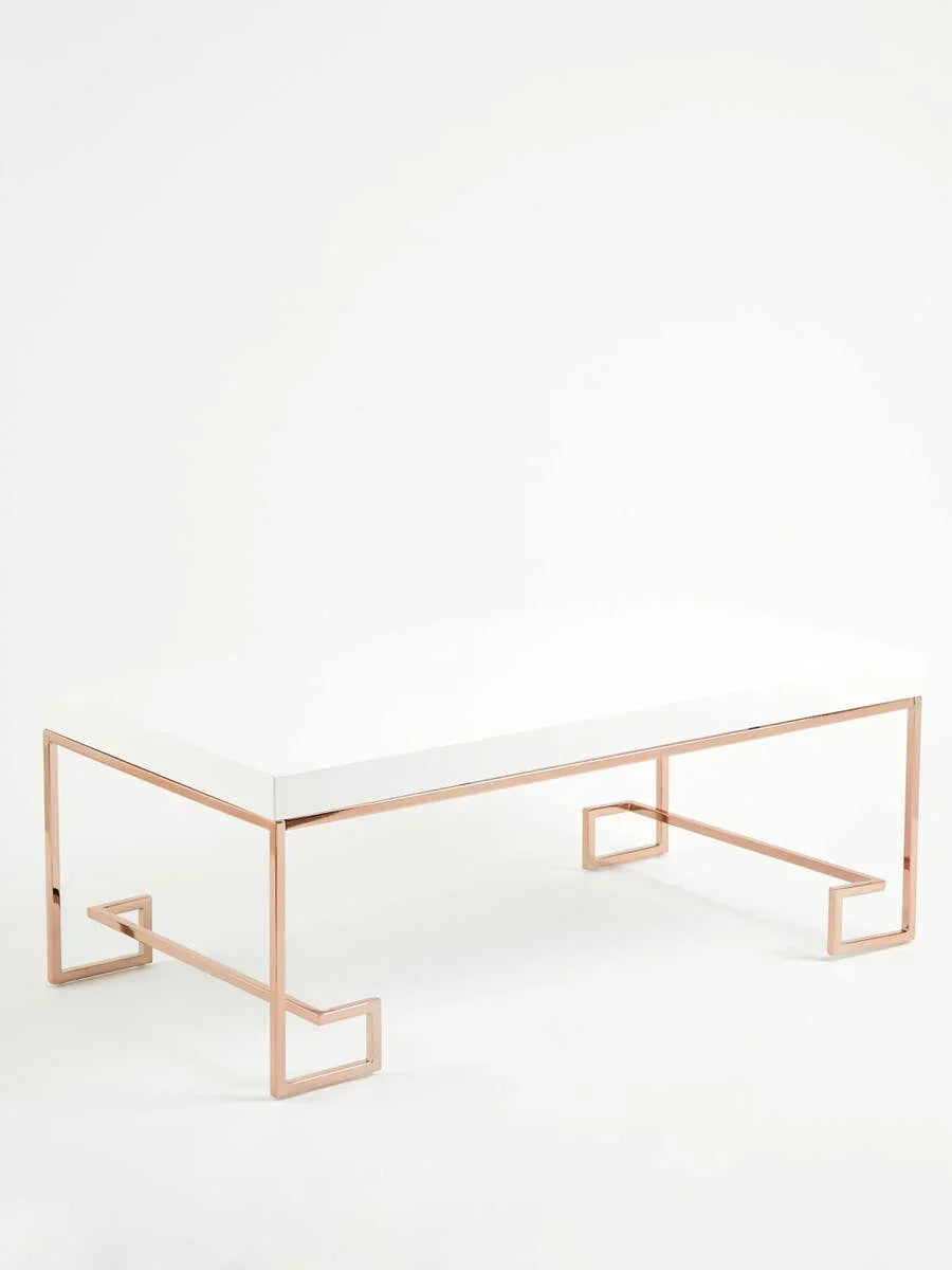 Modern coffee table with white top and gold metal legs in geometric design