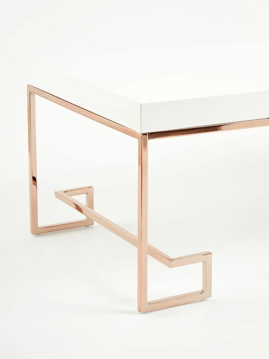White coffee table with rose gold metal geometric legs, side view close-up