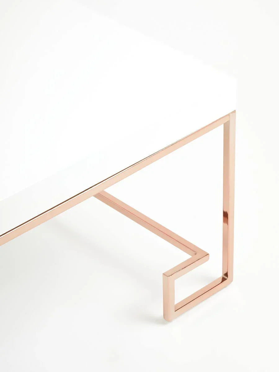 Modern coffee table with white top and rose gold metal frame, corner angle view