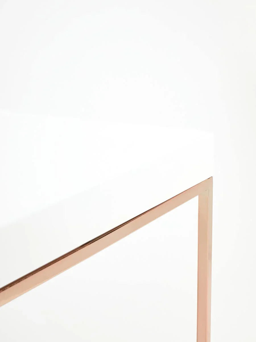White furniture table with gold metal leg detail, close-up corner view
