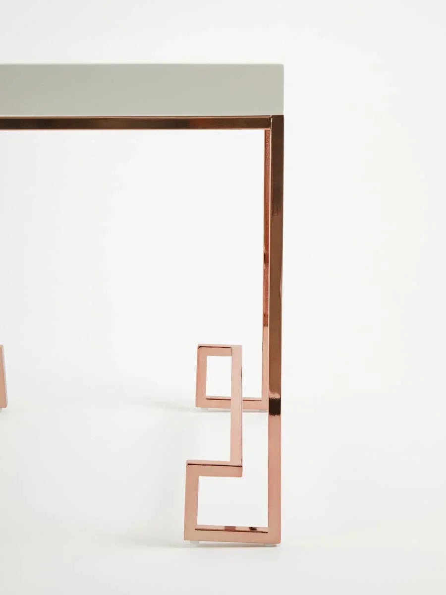 Glass console table with rose gold geometric metal legs, angled side view