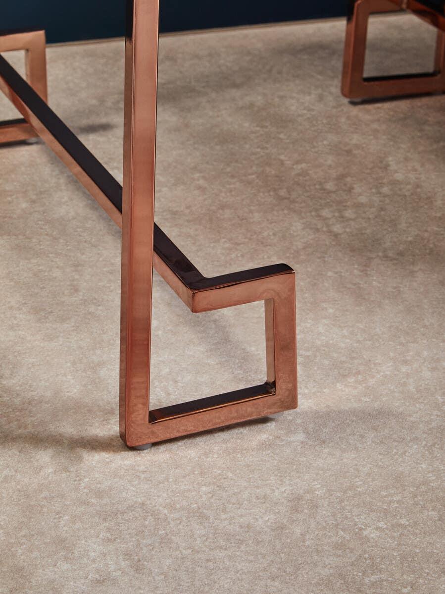 Copper metal table leg with geometric square design on beige carpet