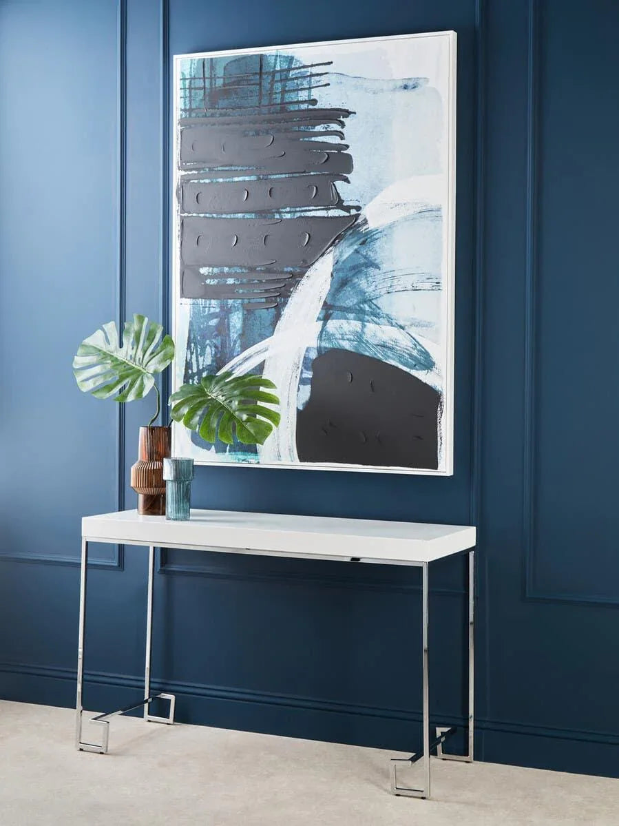 White console table with chrome legs against blue wall, modern abstract art above