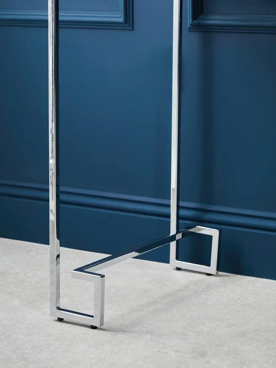 chrome metal table legs with geometric design on light floor and blue wall