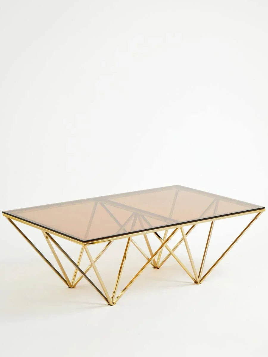 Modern glass coffee table with geometric gold metal base on white background