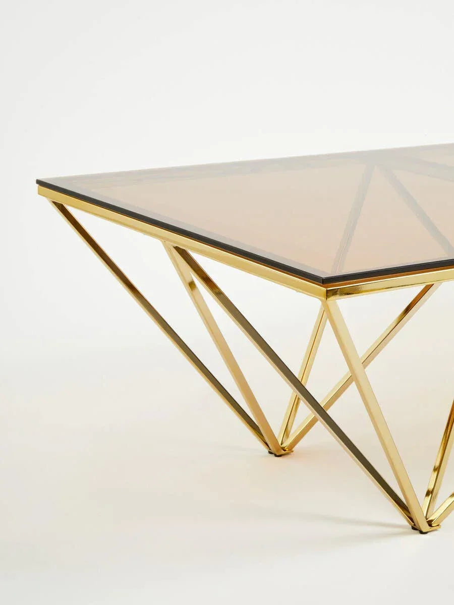 Glass coffee table with gold geometric metal legs, angled side view