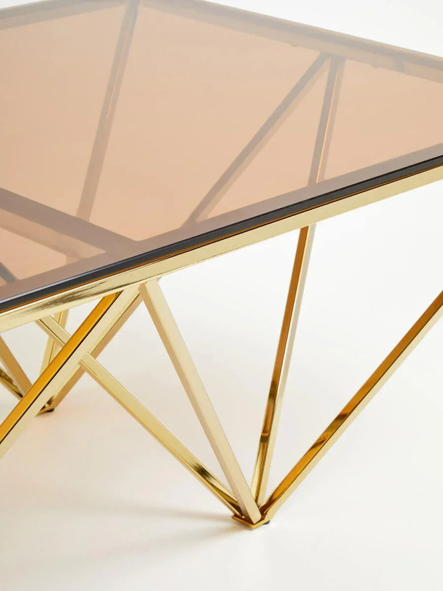Square glass coffee table with gold metal geometric frame, close-up on corner detail