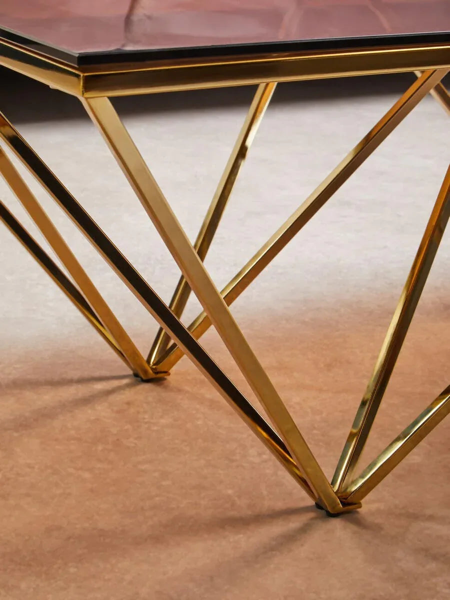 Gold metal coffee table legs with geometric design and glass tabletop corner detail