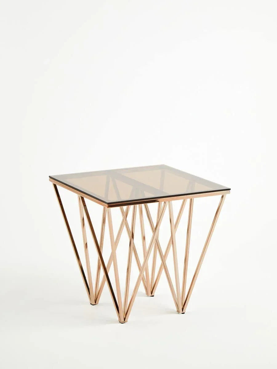 Glass top side table with geometric gold metal base on white background