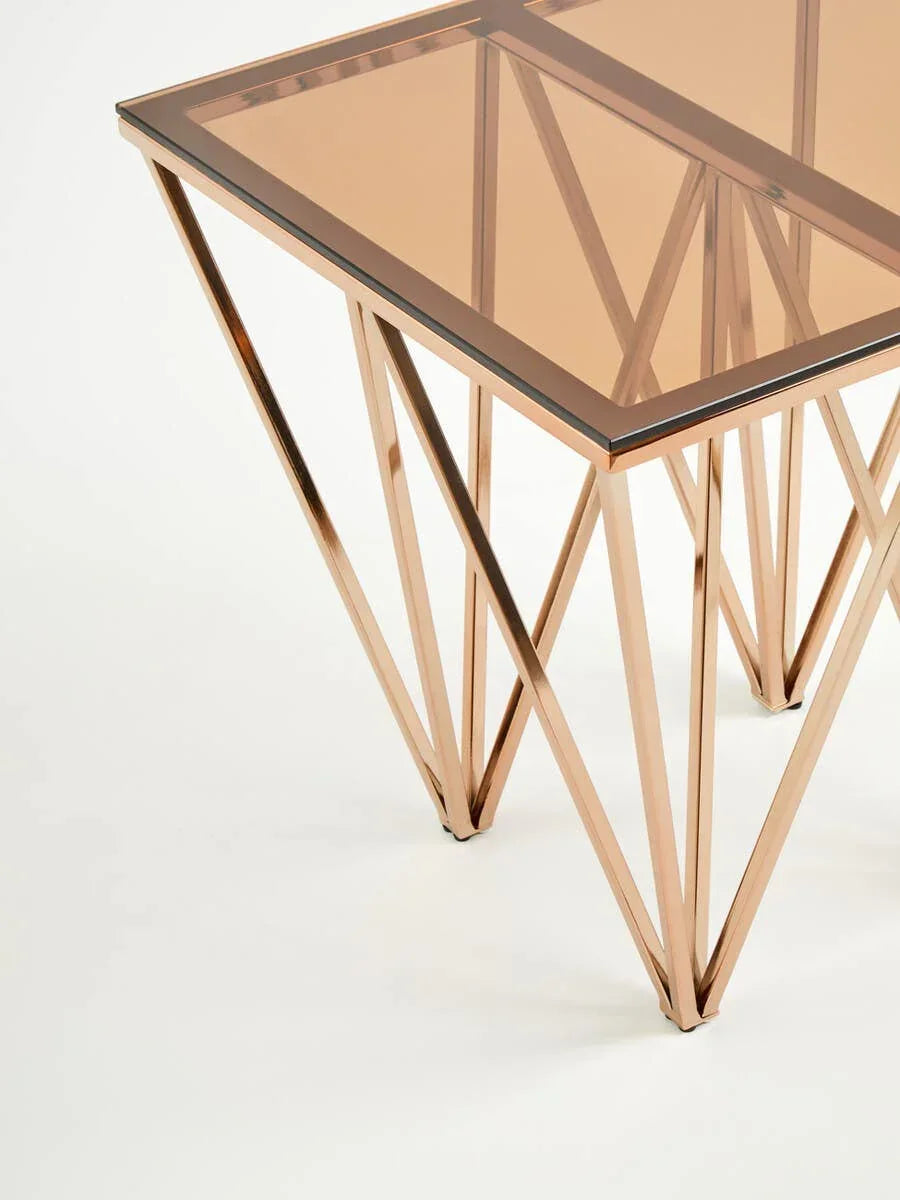 Modern glass top side table with geometric gold metal legs on white background