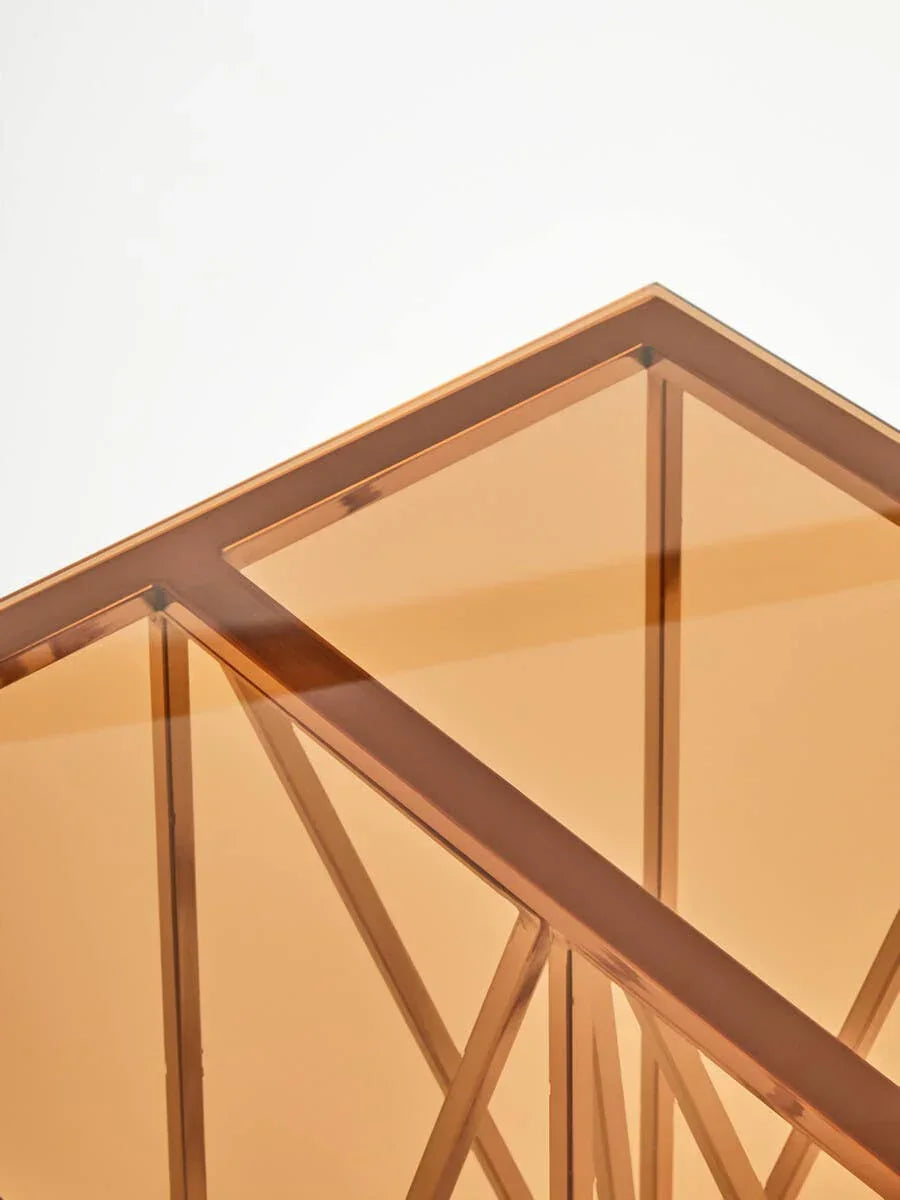 Corner view of glass coffee table with gold metal frame and geometric supports