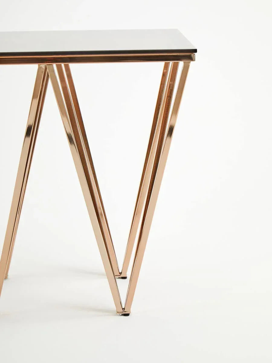 Glass console table with gold metal frame and geometric legs on white background