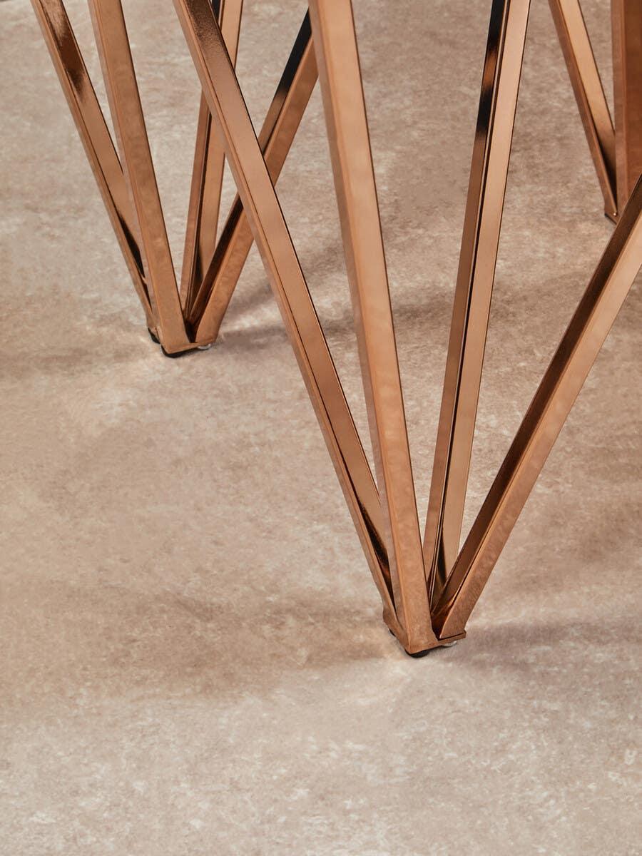 Copper metal table legs with geometric design on stone flooring