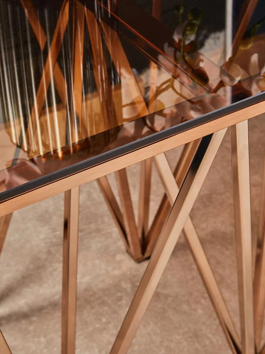 Glass top dining table with gold metal geometric base, close-up of corner and legs