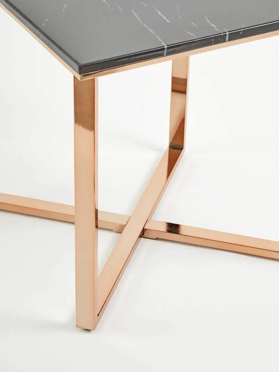 Black marble top dining table with gold metal legs, close-up of corner and base detail