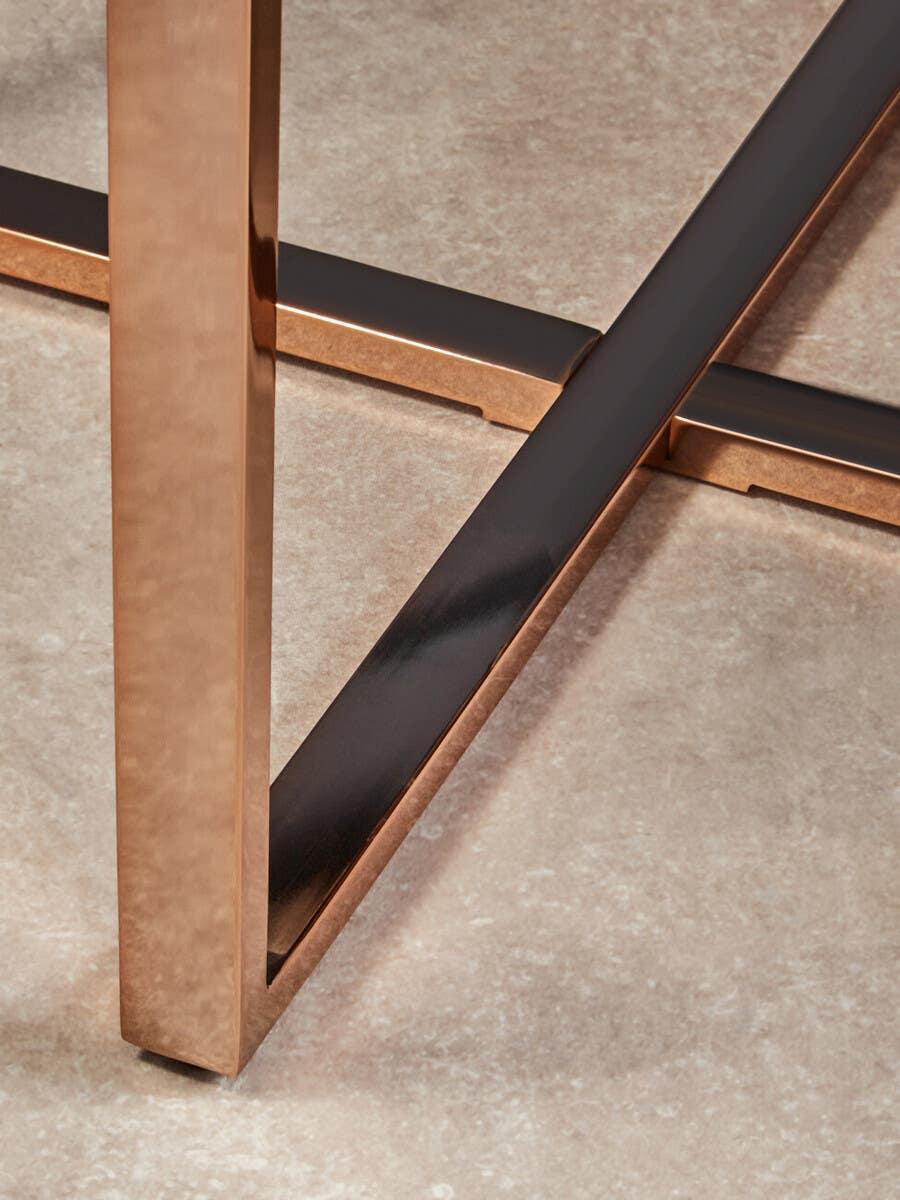 Bronze metal dining table legs with crossbar detail on stone tile floor