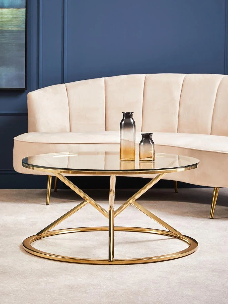 Glass coffee table with gold metal frame in front of cream sofa on beige carpet