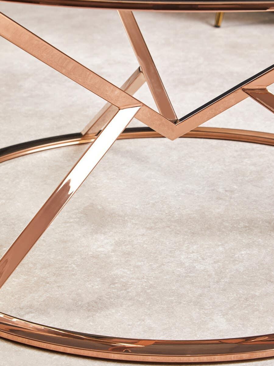 Rose gold metal coffee table base with geometric design on light carpet