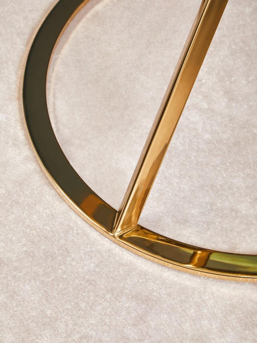 Gold metal table leg base detail on cream carpet