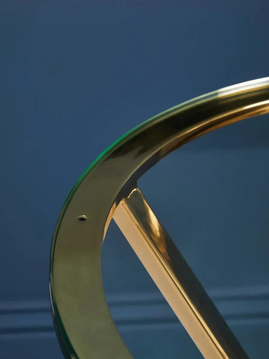 Glass top table with gold metal frame close-up against blue wall