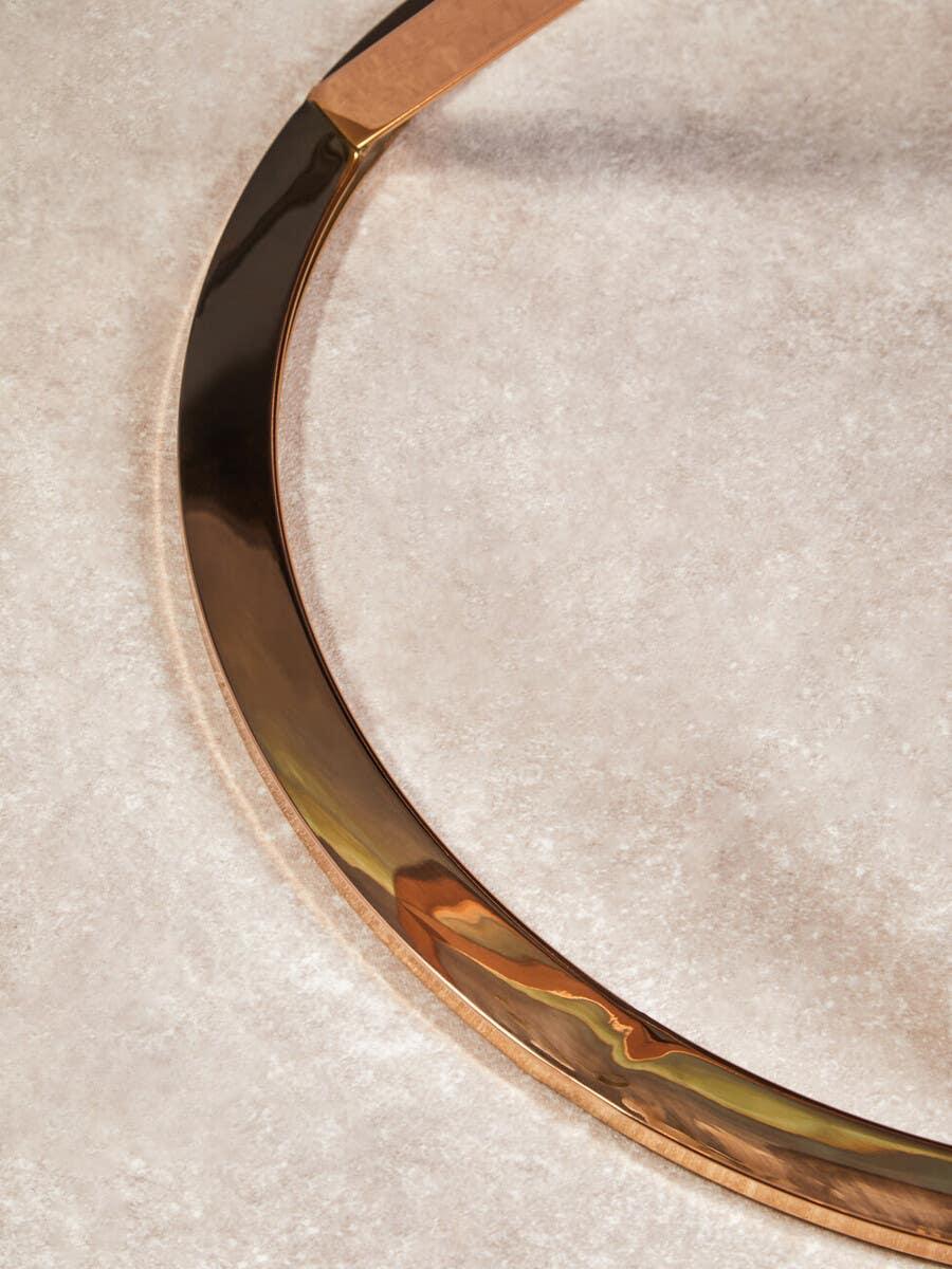 Round gold metal furniture leg on light marble tile floor
