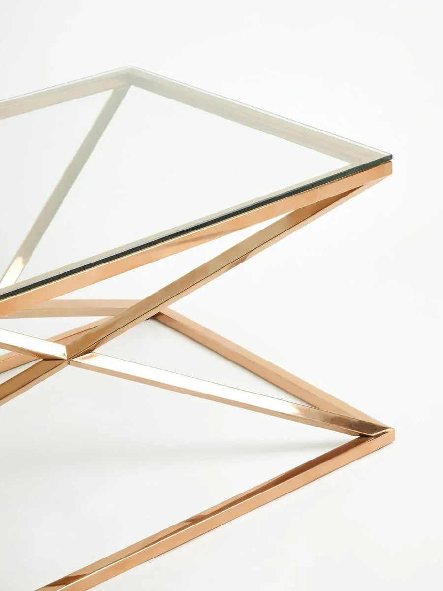 Glass coffee table with gold metal geometric base on white background