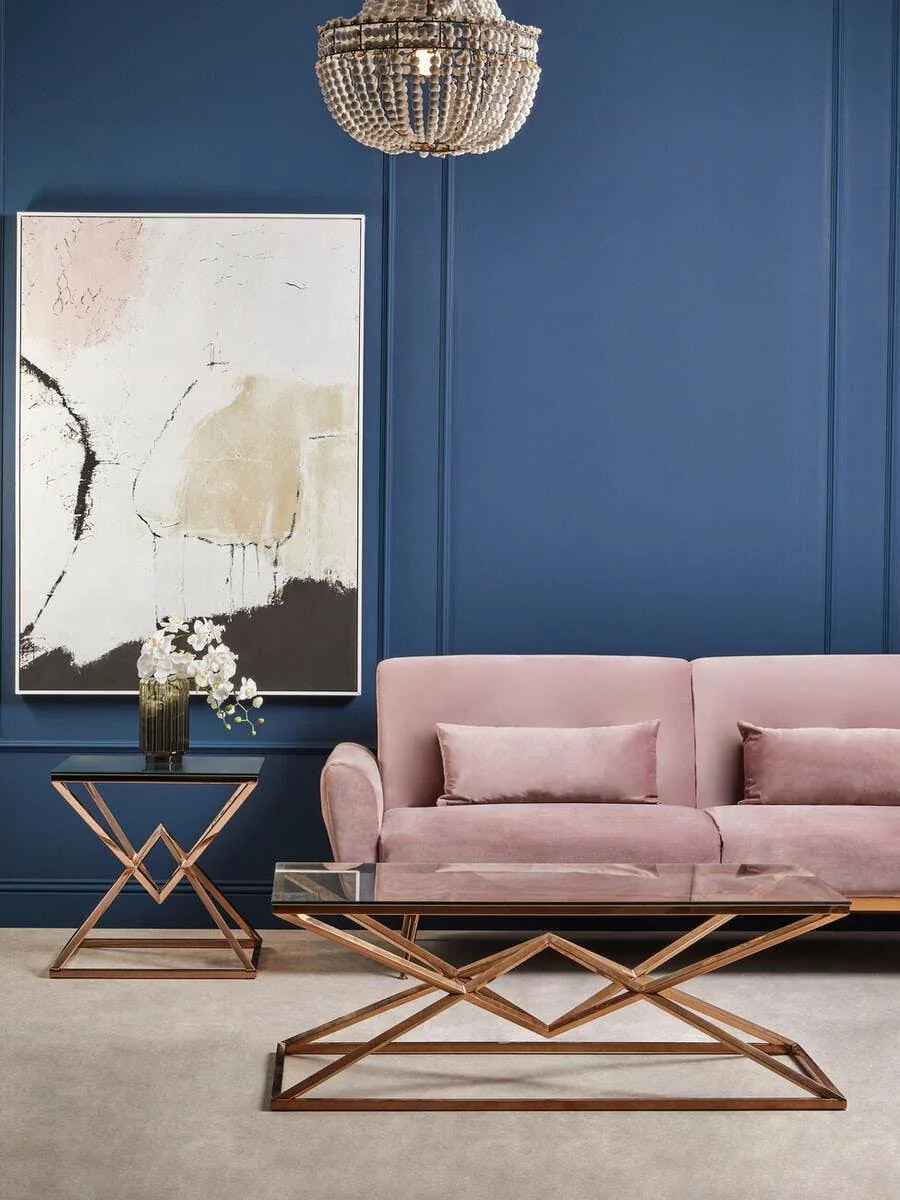 Velvet sofa with gold metal and glass coffee table set against blue wall and abstract art
