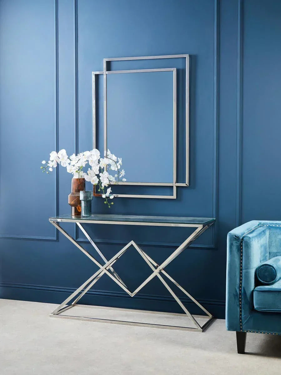 Modern glass console table with chrome frame and decor against blue panel wall