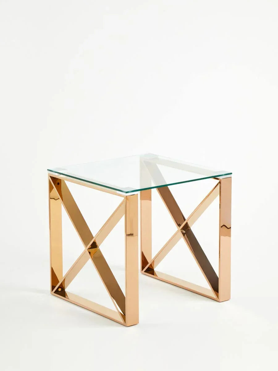 Glass top side table with gold metal crossed frame on white background