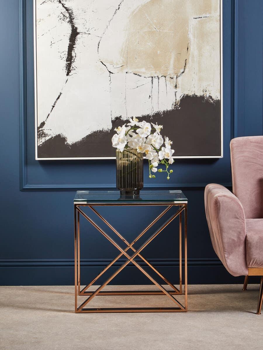 Glass top side table with gold metal frame and vase of white flowers in modern living room