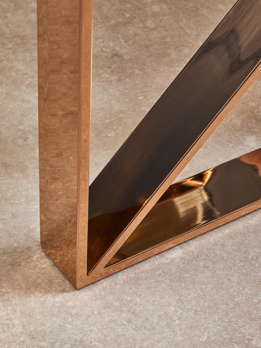 Brushed gold metal table leg with diagonal support on light stone floor