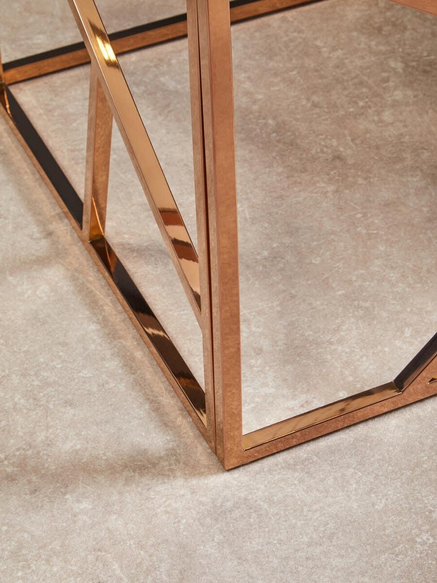 Rose gold metal table legs with geometric design on beige tiled floor