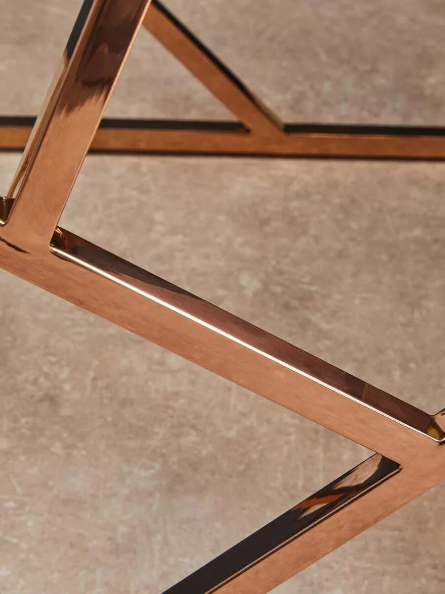 Closeup of metallic table leg with rose gold finish on stone floor