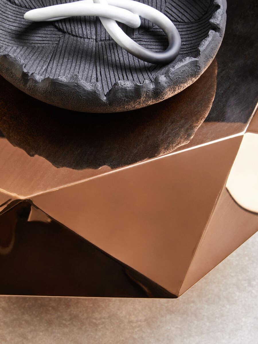 Geometric bronze coffee table with decorative textured black bowl and ceramic accent