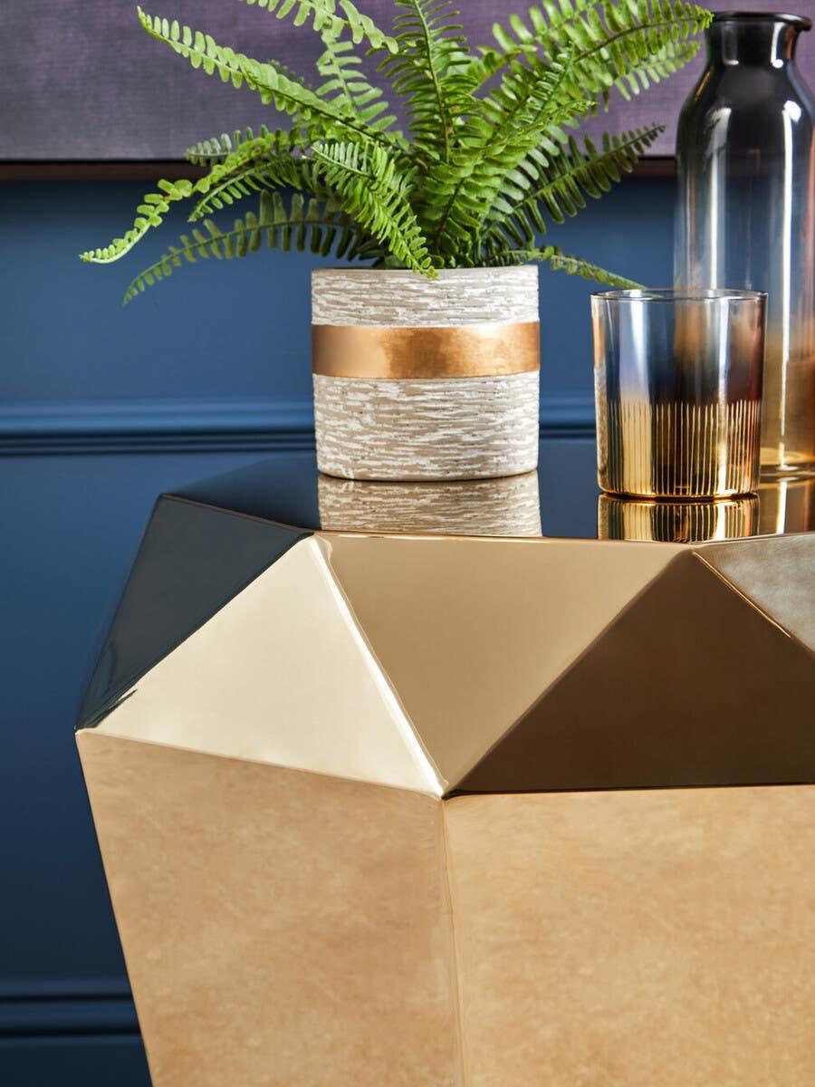 Gold geometric side table with potted fern and modern glass decor