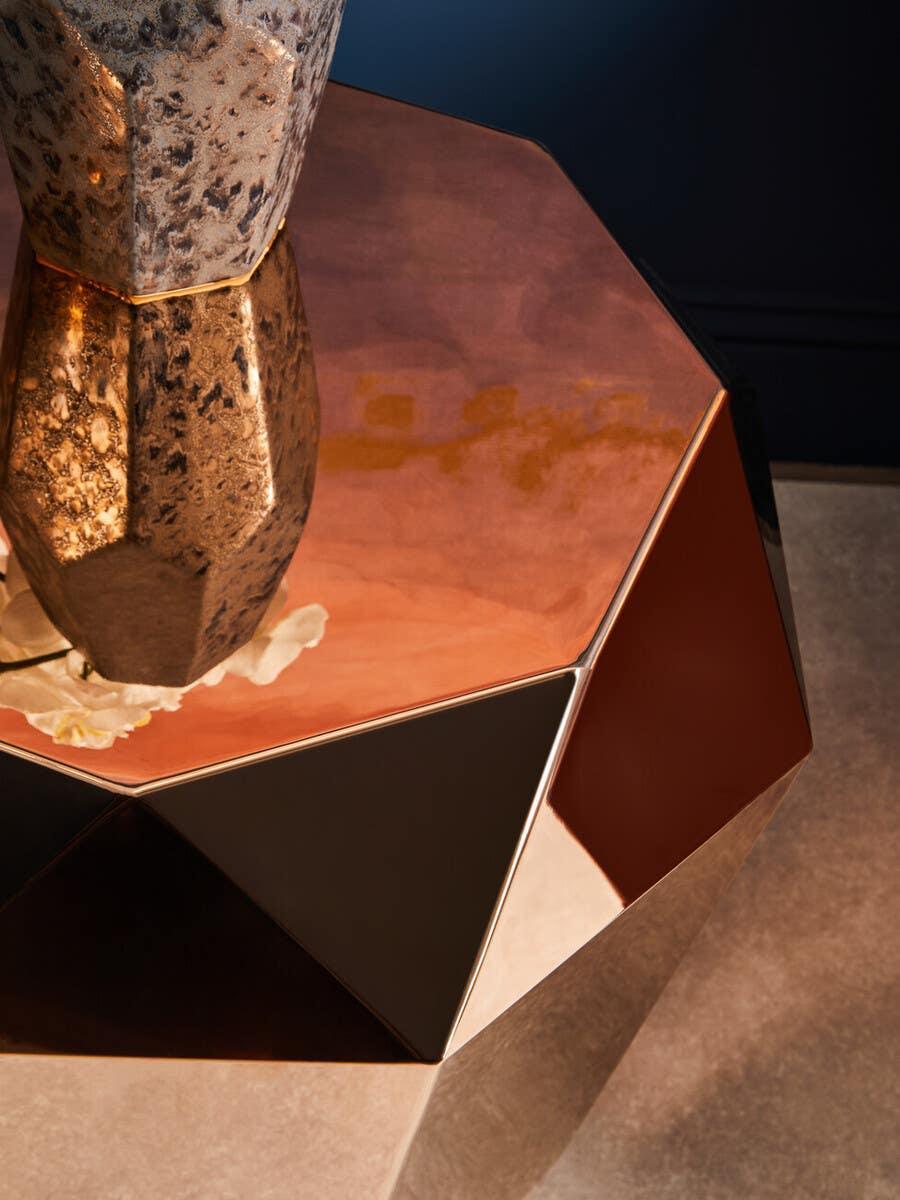 Geometric copper metal coffee table with reflective surface and stone vase detail