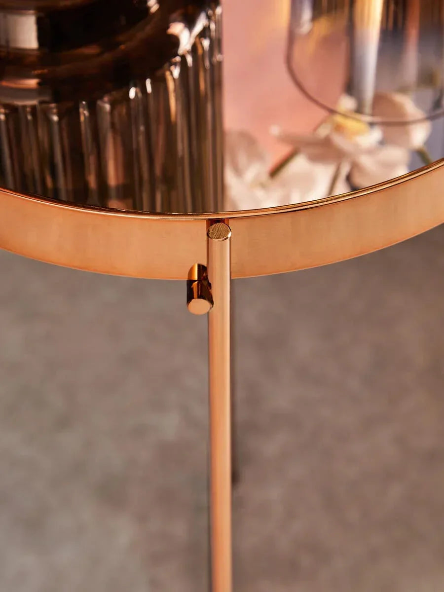 Round gold side table with glass top and metal frame, close-up of leg and edge