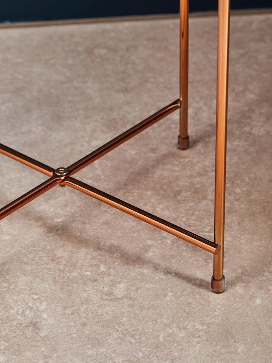 Copper metal table legs with crossbar support on a beige tiled floor