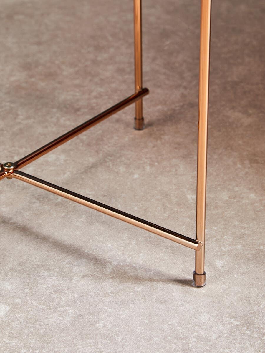 Gold metal table legs with crossbar detail on stone effect floor