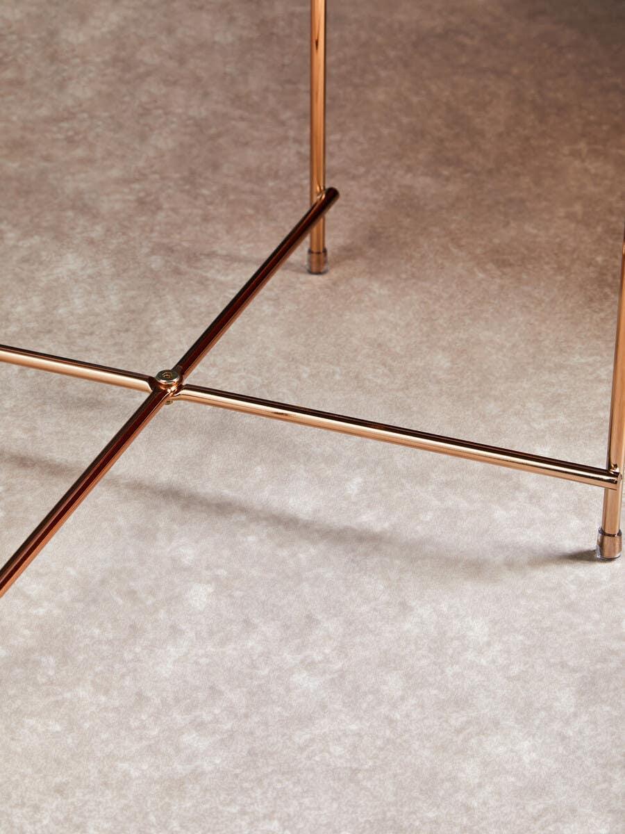 Gold metal table legs with crossbar detail on light textured flooring
