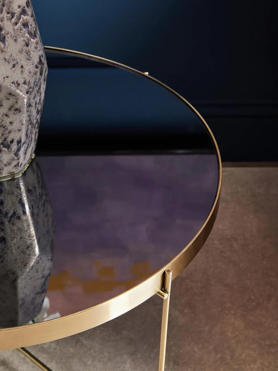 Round glass side table with gold metal frame and decorative ceramic vase