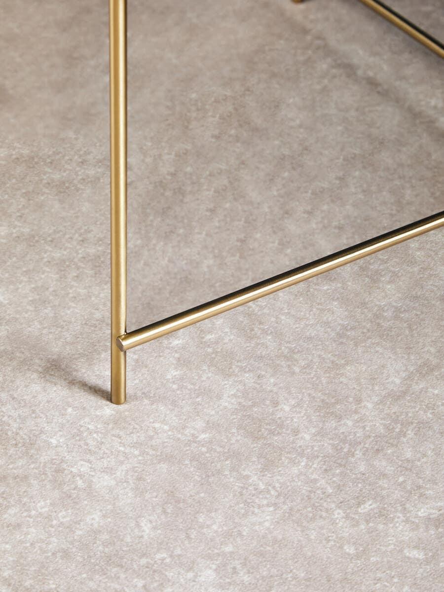 Gold metal table leg and frame on light textured carpet